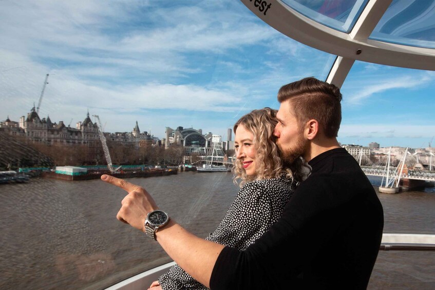 A couple on a boat pointing towards a cityscape with historic buildings and a modern bridge. 3