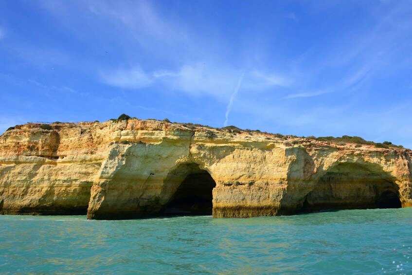 A coastal rock formation with a natural arch and clear turquoise waters. 5