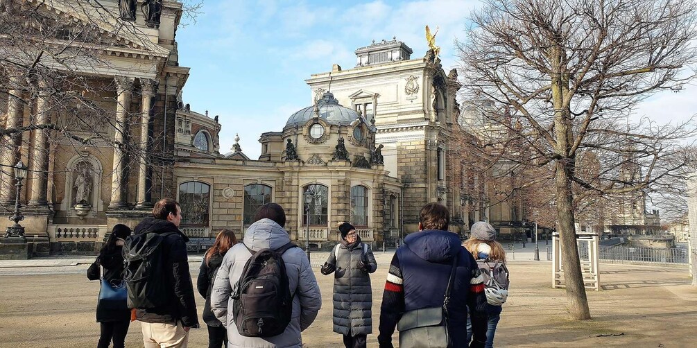 A group of people standing in front of a historic building with classical architecture. 2