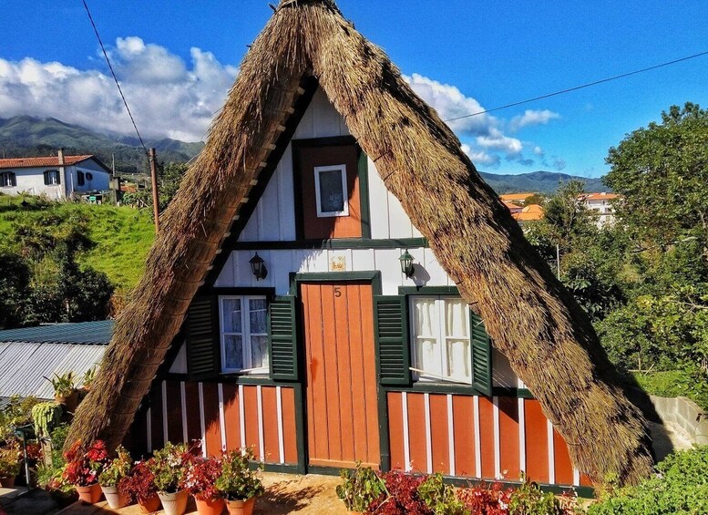 A traditional house with a thatched roof, green shutters, and a number '5' on the door. 5