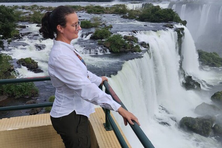 A person standing on a viewing platform overlooking a waterfall. 3