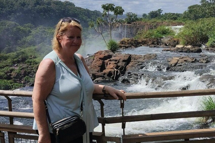 A person standing by a river with a waterfall in the background. 3