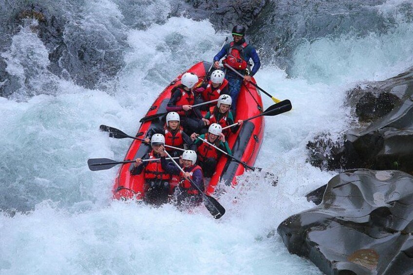 A group of people in a red raft navigating through a turbulent river. 1
