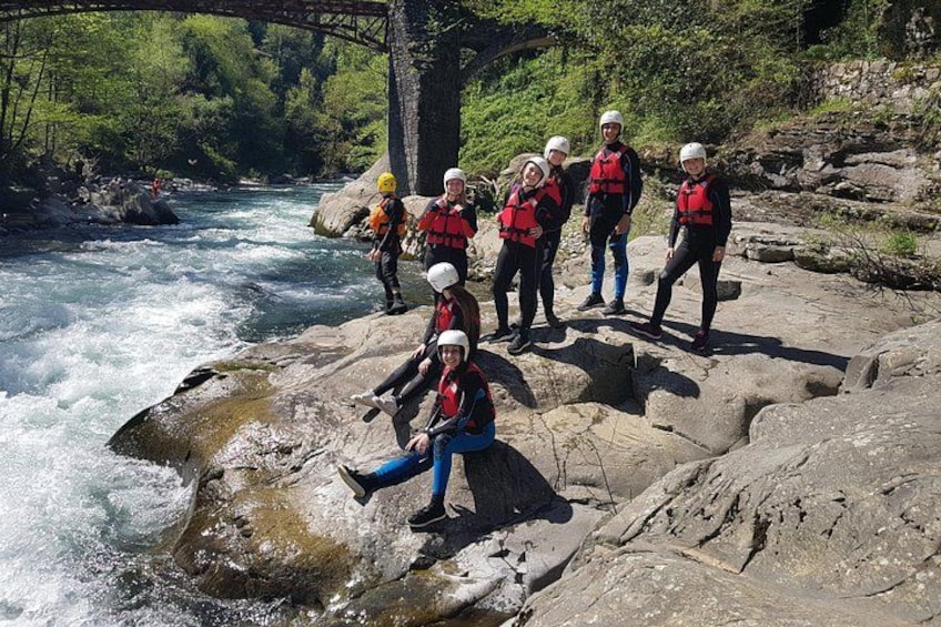 A group of people in life jackets and helmets on a rocky riverbank. 5