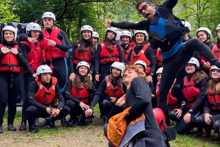 A group of people wearing helmets and life vests, gathered outdoors in a wooded area. 3