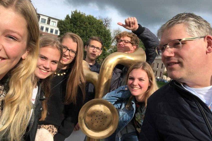 A group of people holding a large golden number '1' and a brass instrument. 5