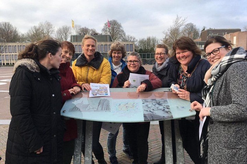 A group of people around a table with a map and papers. 1