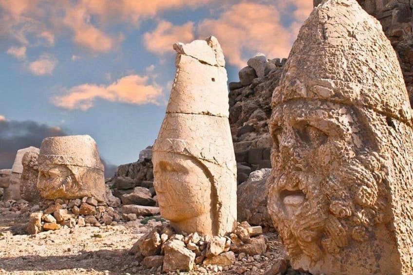 Ancient stone structures with carved faces, set in a rocky landscape. 4