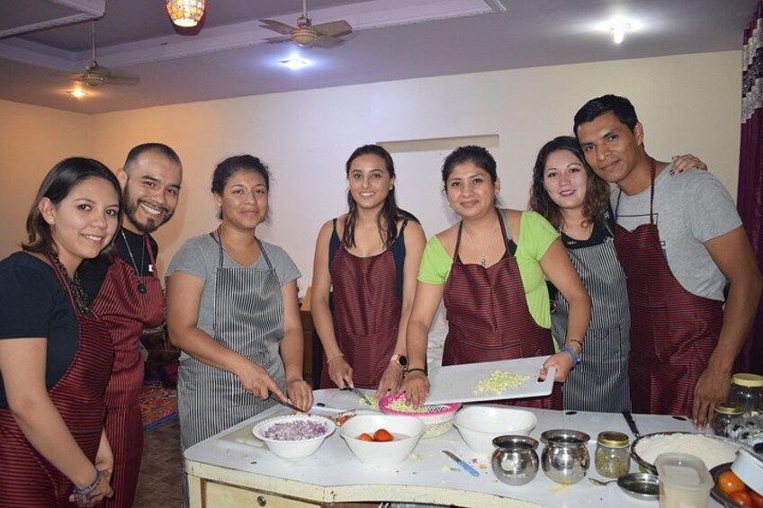 Un grupo de personas con delantales, reunidas alrededor de una mesa con ingredientes y utensilios de cocina. 1
