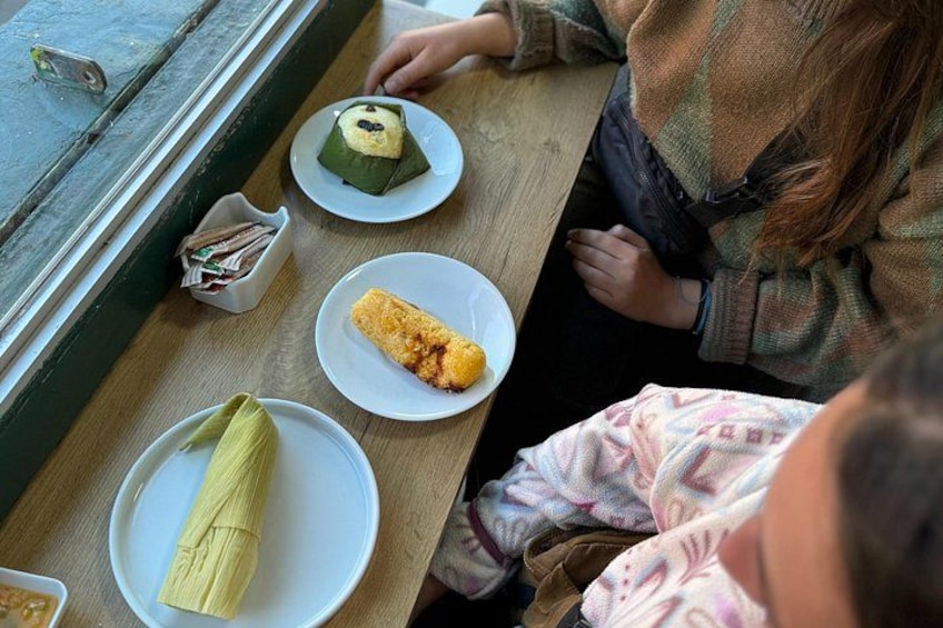A table with food items, including a wrapped dish, a plate with a yellow food item, and a plate with a green food item. 2