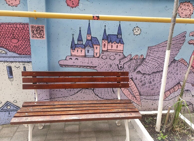 Un banco frente a un mural con un castillo y un dragón. 4