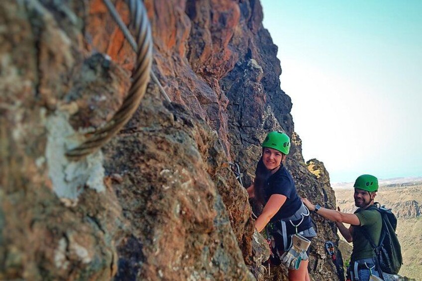Two people climbing a rocky cliff with safety ropes. 4