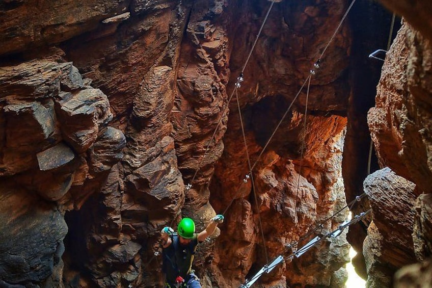 A person rappelling down a rocky cliff with a harness and ropes. 3