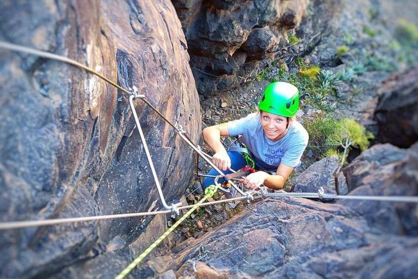 A person climbing a rocky terrain with ropes. 2