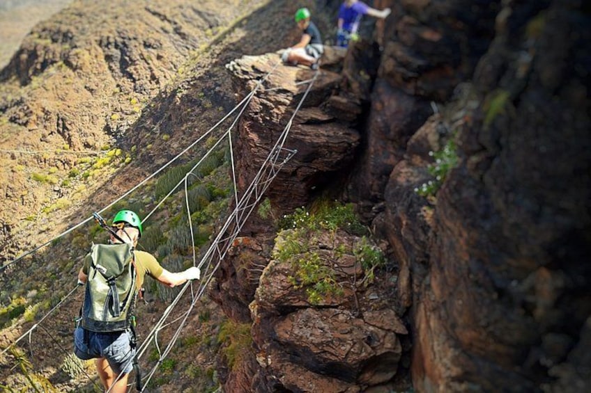 A person crossing a suspension bridge in a rocky canyon. 3