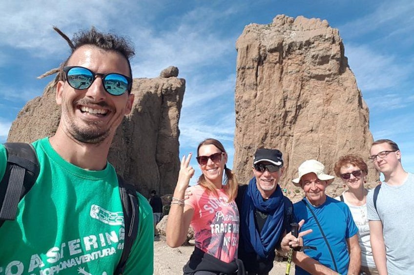 A group of people in front of a large rock formation. 3