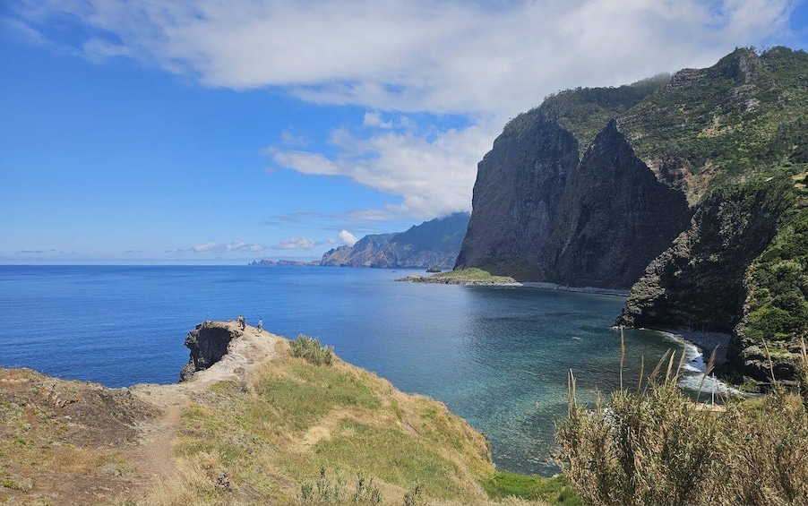 A coastal landscape with cliffs, a clear blue sea, and a narrow path leading to the water. 4