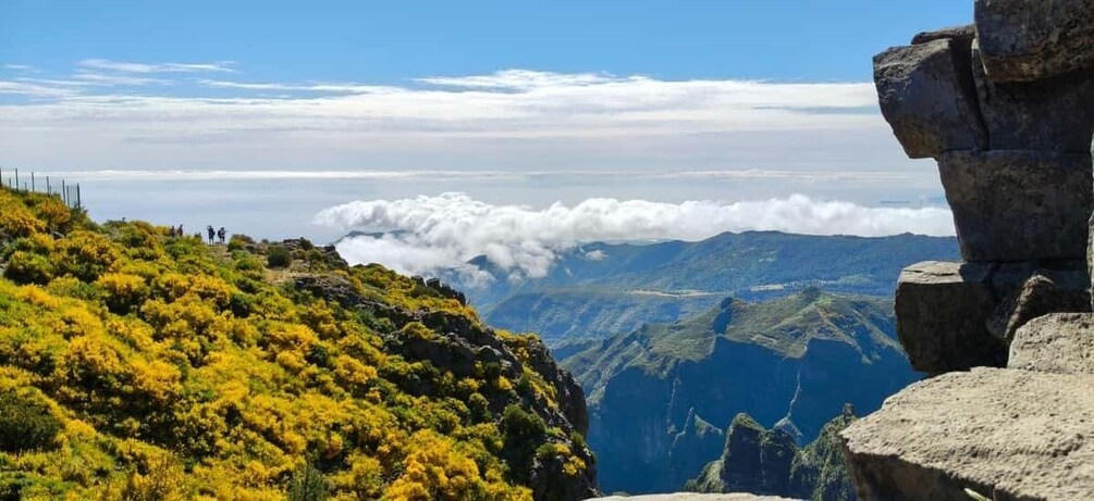A mountainous landscape with a clear sky, a rocky outcrop, and a trail with hikers. 2