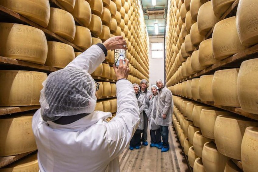 Una persona fotografiando a un grupo de personas en un almacén de queso. 1