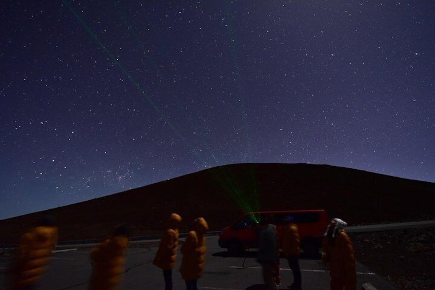 A starry night sky, a red vehicle, and a group of people. 2