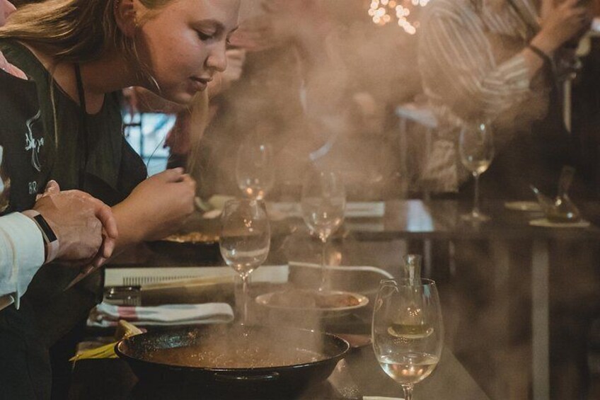 Un gruppo di persone cena in un ristorante, con una padella sul tavolo e bicchieri di vino. 5