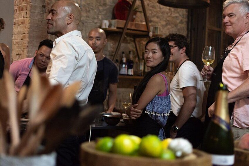 Un gruppo di persone riunite in un ambiente conviviale, con una bottiglia di vino e una ciotola di frutta sul tavolo. 2