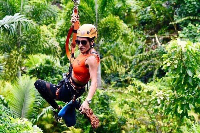 A person zip-lining through a dense, green forest. 5
