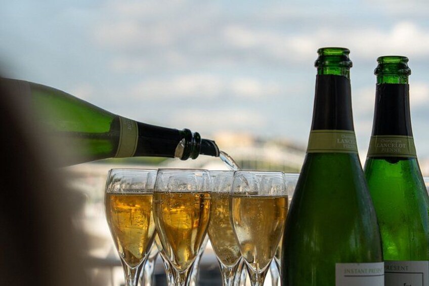 Une bouteille de champagne est versée dans des verres, et deux autres bouteilles sont visibles à l’arrière-plan. 2