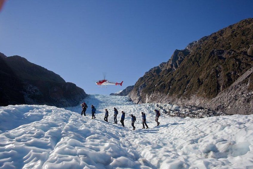 A group of people on a snowy mountain with a helicopter flying overhead. 4