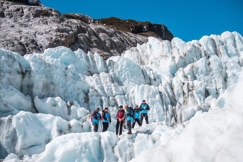 A group of people standing on a glacier with a mountain in the background. 3