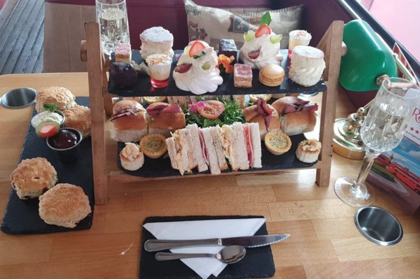 A variety of sandwiches, pastries, and a glass of water on a table. 3