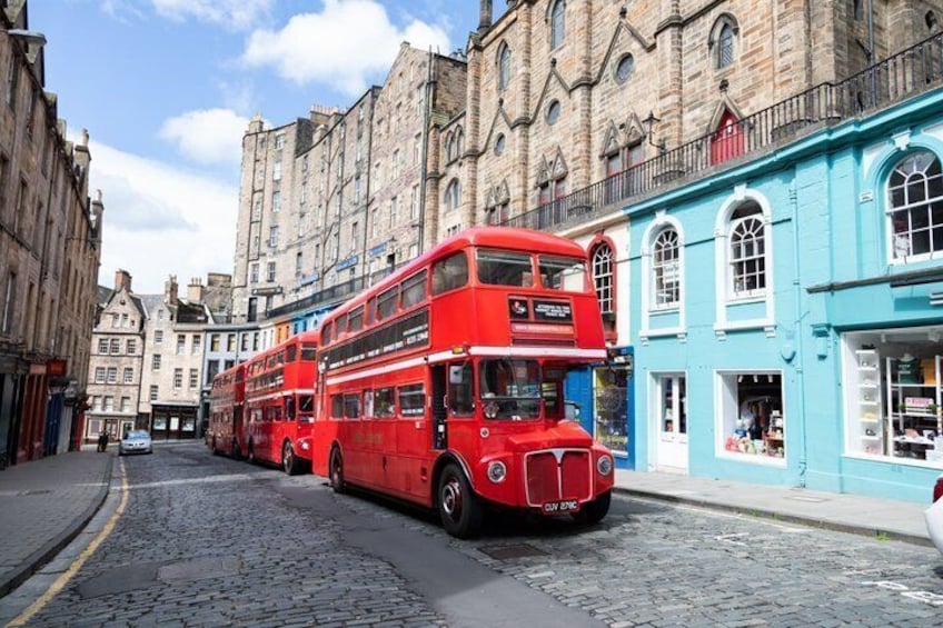A red double-decker bus on a cobblestone street in front of historic buildings. 2