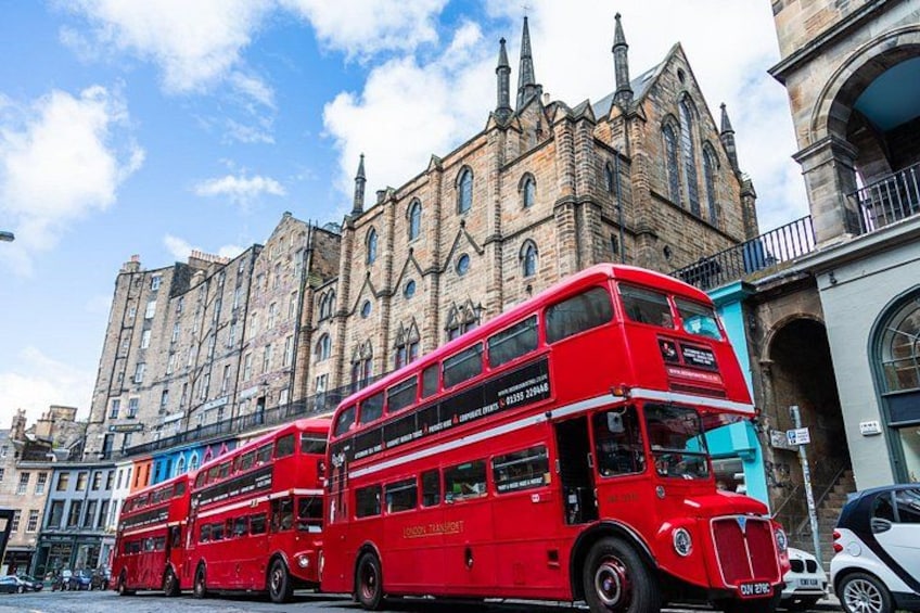 A red double-decker bus in front of a historic building with multiple spires. 2