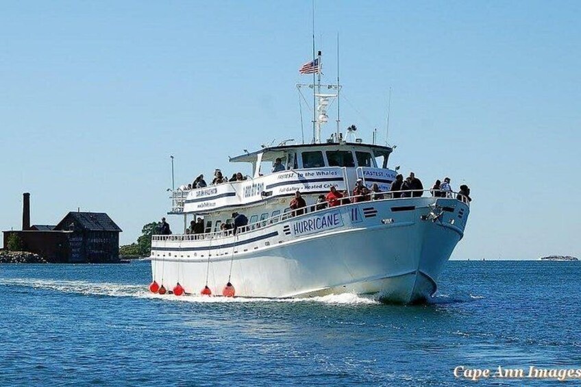 A white boat named 'Hurricane' with passengers, moving on the water. 2