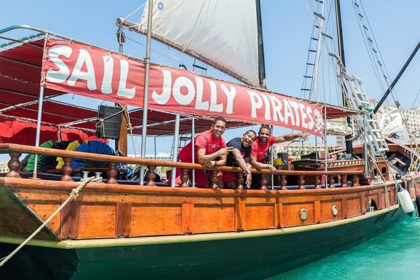 Eine Segelyacht mit rotem Segel, beschriftet mit 'SAIL JOLLY PIRATES', und einer Leiter auf dem Deck. 2
