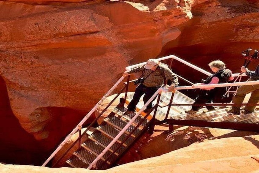 A person climbing a metal staircase in a canyon with red rock walls. 4