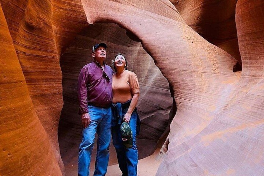A couple standing in a narrow canyon with smooth, reddish rock walls. 3