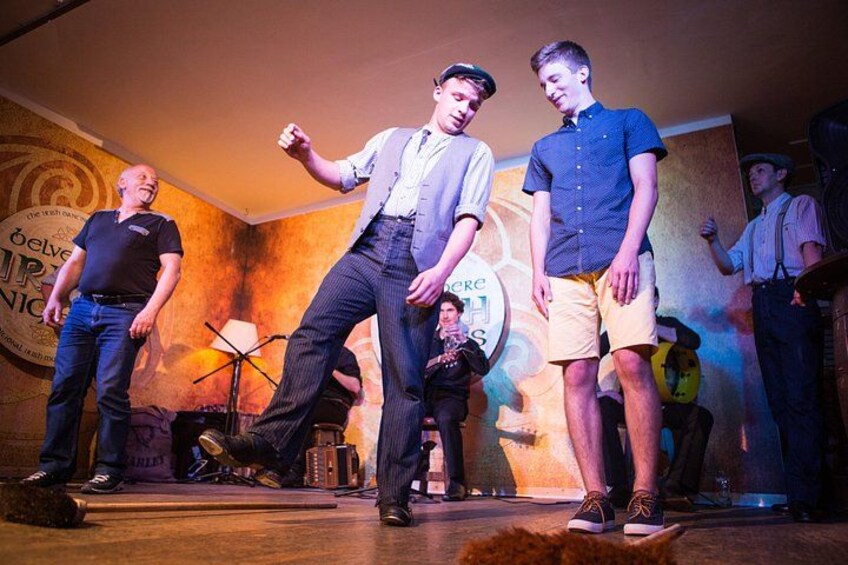 A stage with people performing, a drum set, and a microphone stand. 2