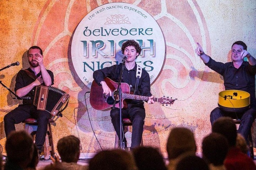 Una banda actuando en el escenario con un fondo que dice 'The Irish Dancing Experience'. 3