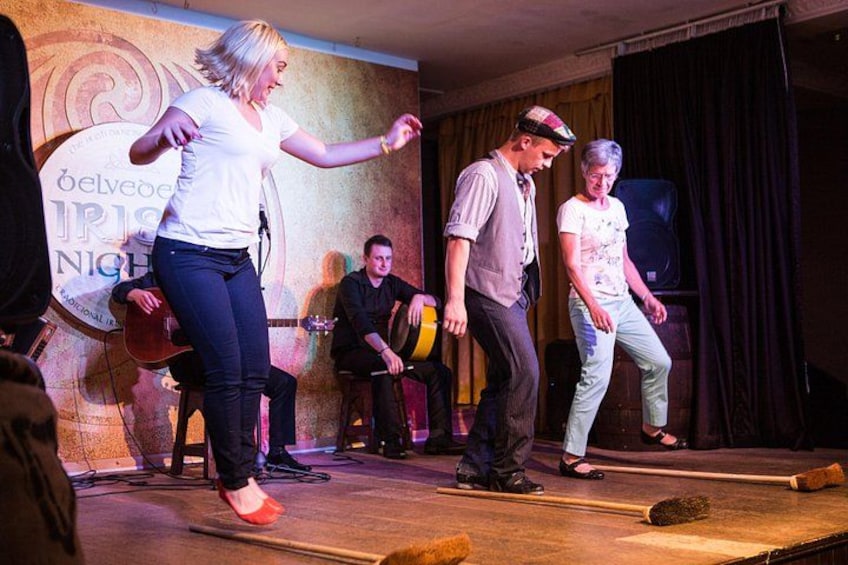 A stage with a band performing, a woman dancing, and a man playing a guitar. 2