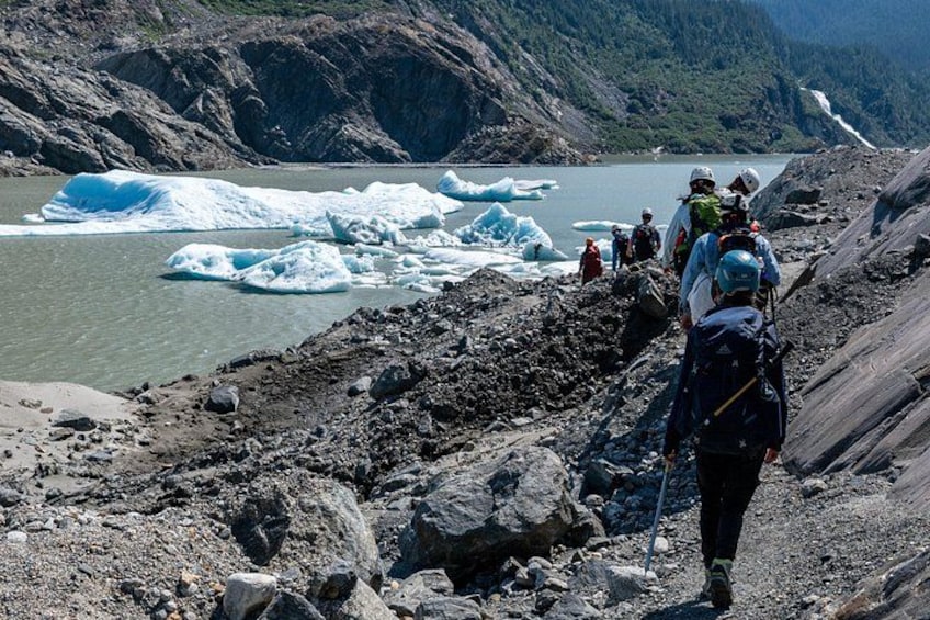 Un groupe de randonneurs sur un sentier rocailleux, avec un glacier en arrière-plan. 5