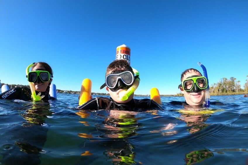 Tres personas haciendo snorkel en aguas cristalinas bajo un cielo despejado. 2