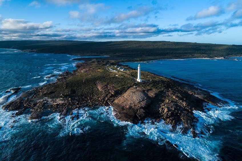 A lighthouse on a rocky island surrounded by ocean waves. 1