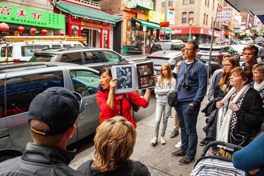 On a walking tour of Chinatown in San Francisco, a guide holds aloft a binder full of photos. 5