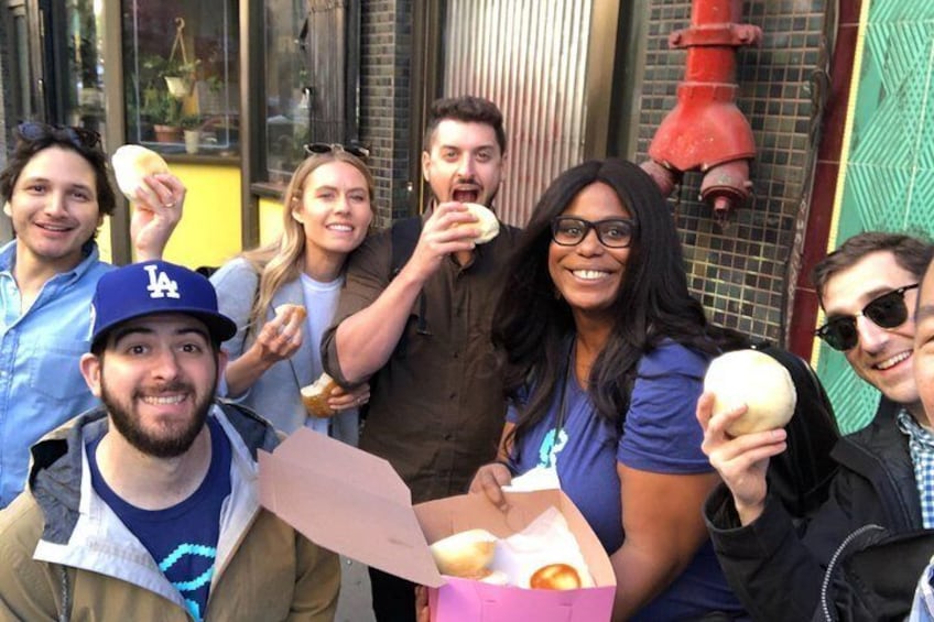 Eine Gruppe von Menschen hält Donuts vor einem Gebäude, an dem ein roter Feuerlöscher steht. 4