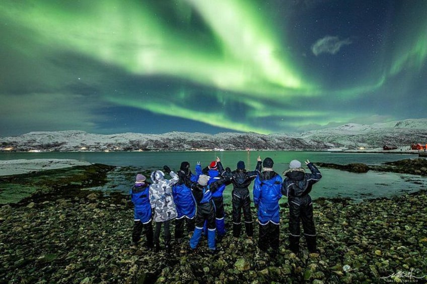 Un gruppo di persone ammira l'aurora boreale su un paesaggio innevato. 2