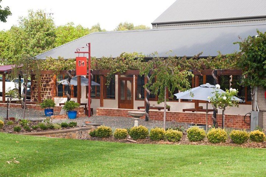 A building with a brick facade, wooden pergola, and potted plants. 2