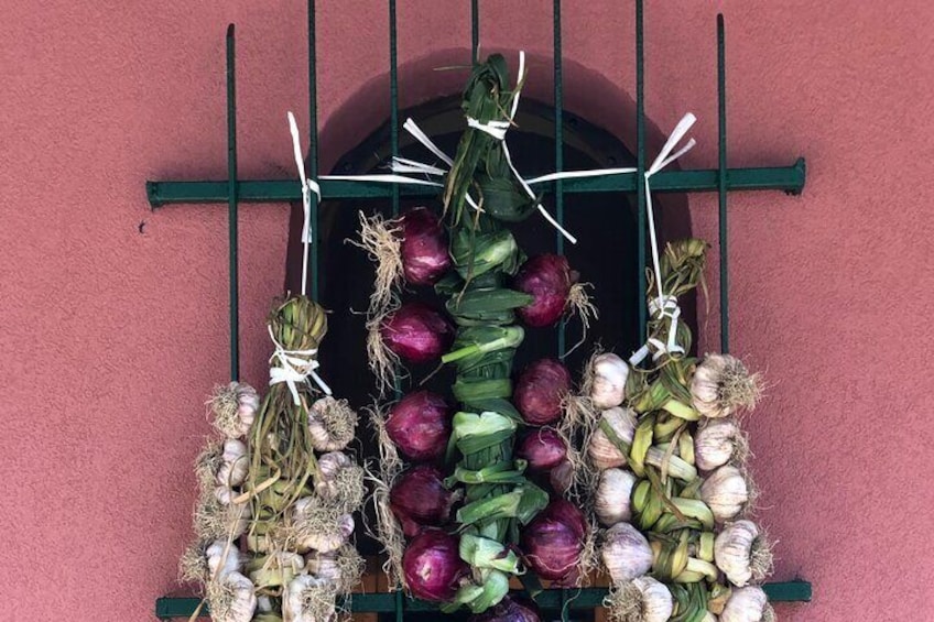 Una ventana con varios vegetales colgados en un estante. 2