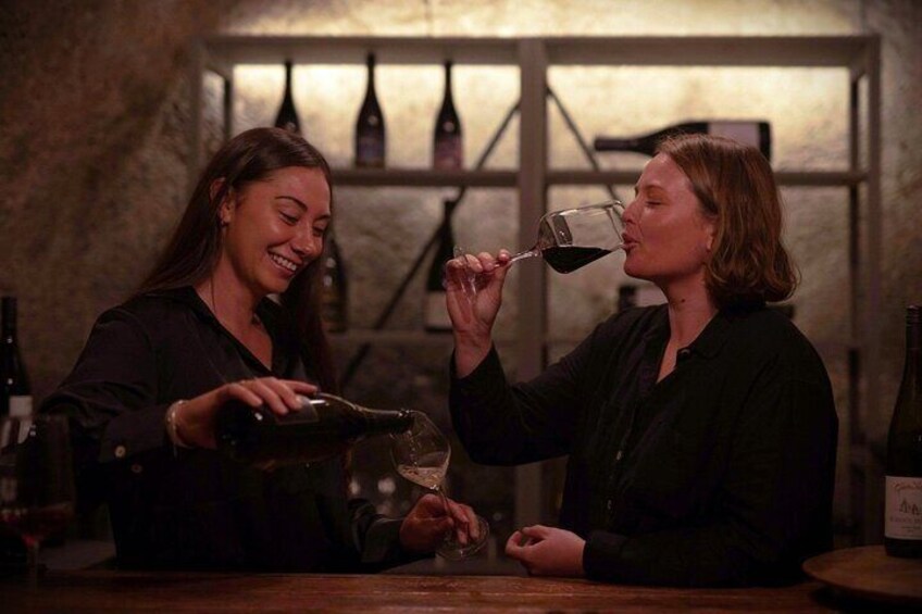 To personer hælder vin op i glas på en bar. 2