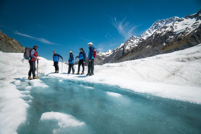 Un grupo de personas sobre un glaciar, con montañas al fondo. 3
